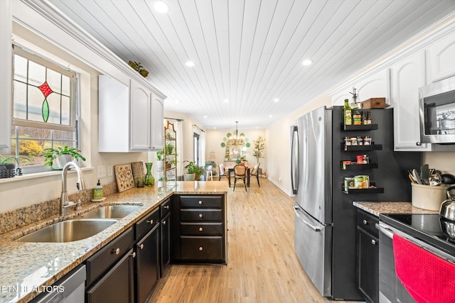 kitchen with a sink, a wealth of natural light, appliances with stainless steel finishes, and white cabinets