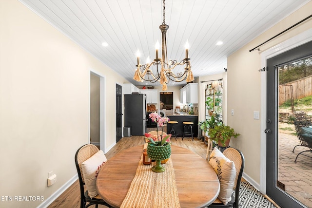 dining area with wood ceiling, a healthy amount of sunlight, a chandelier, and light wood finished floors