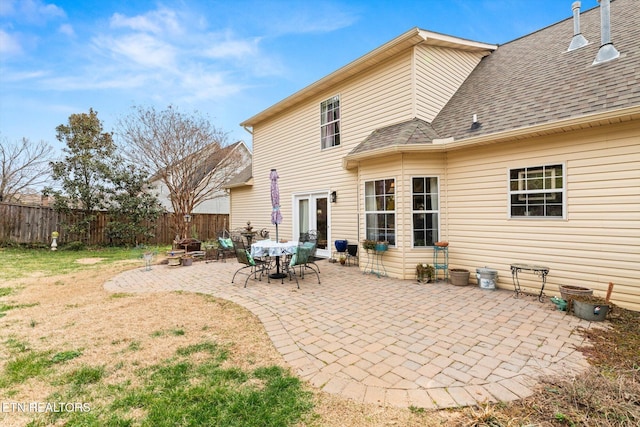 rear view of house with a shingled roof, a fire pit, fence, a lawn, and a patio area