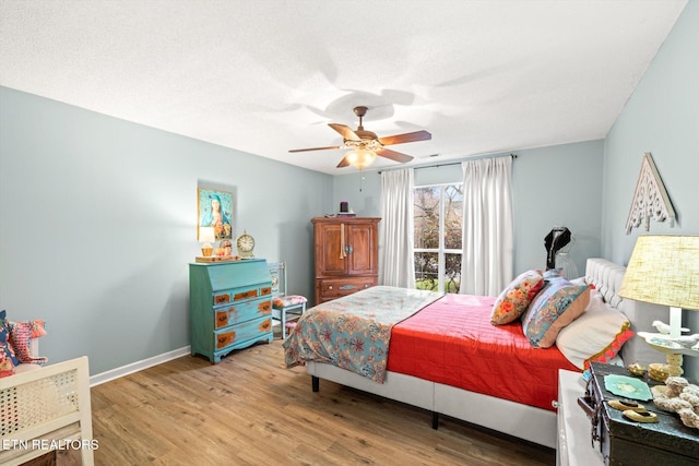 bedroom with a textured ceiling, baseboards, light wood-type flooring, and a ceiling fan