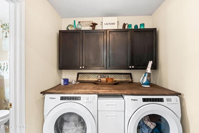 washroom featuring a textured ceiling, cabinet space, and washer and clothes dryer