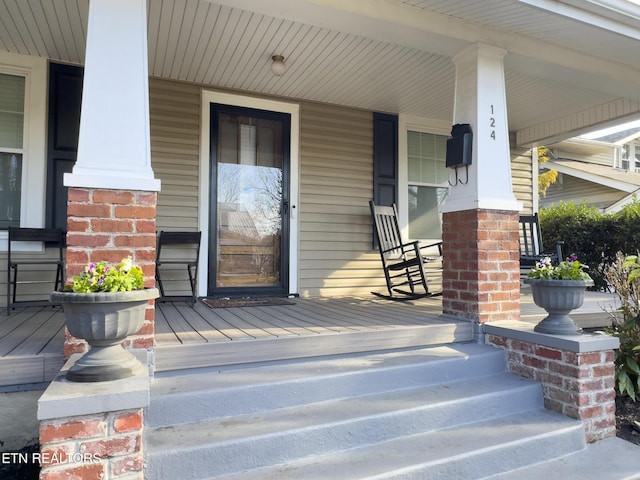 doorway to property featuring brick siding and a porch