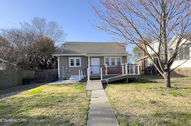 bungalow with a deck, a front lawn, a fenced backyard, and roof with shingles