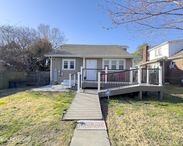 bungalow featuring a wooden deck, a patio, a front yard, and fence