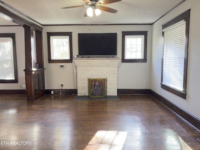 unfurnished living room featuring wood finished floors, baseboards, a fireplace with flush hearth, ceiling fan, and ornamental molding