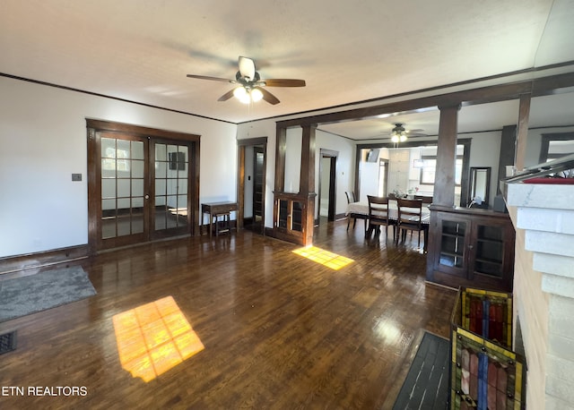 living area featuring a ceiling fan, wood finished floors, decorative columns, a fireplace, and french doors