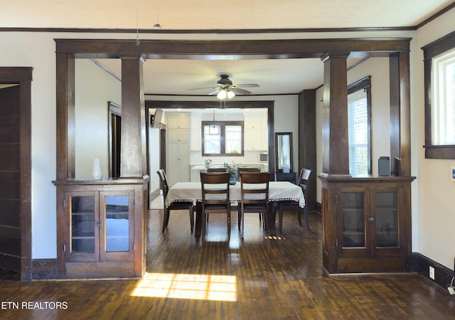 dining space with baseboards, ornamental molding, decorative columns, a ceiling fan, and dark wood-style flooring