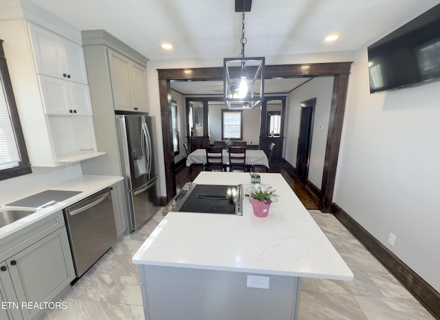 kitchen with baseboards, gray cabinets, appliances with stainless steel finishes, decorative light fixtures, and a center island