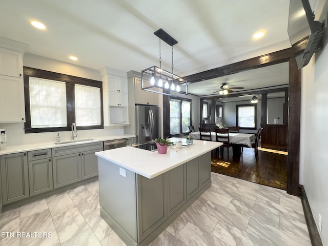 kitchen with a center island, light countertops, gray cabinets, appliances with stainless steel finishes, and a sink