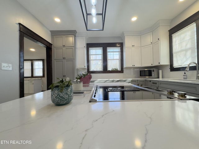 kitchen with decorative backsplash, stainless steel microwave, a healthy amount of sunlight, and a sink