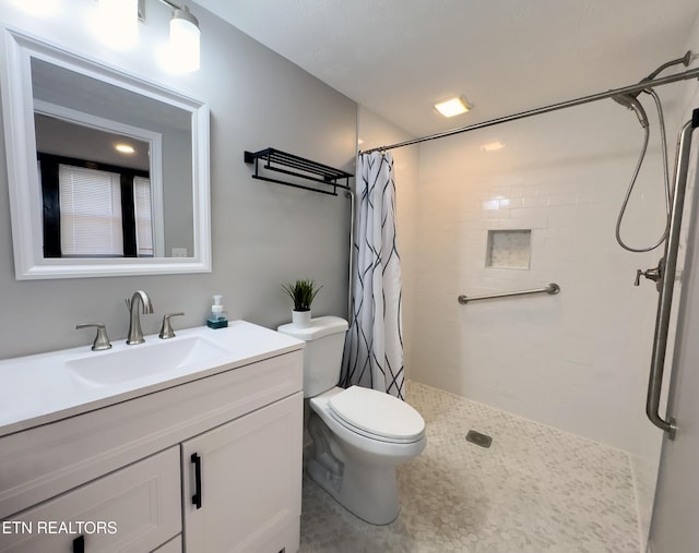 bathroom featuring toilet, tiled shower, and vanity