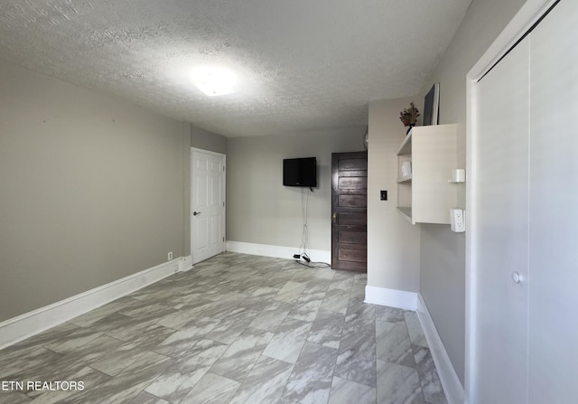 spare room featuring baseboards and a textured ceiling