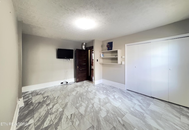 unfurnished bedroom featuring a closet, a textured ceiling, and baseboards