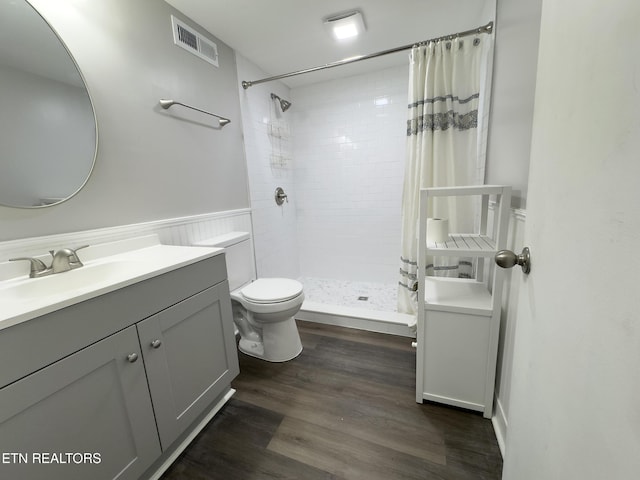 full bath with vanity, wood finished floors, visible vents, wainscoting, and toilet