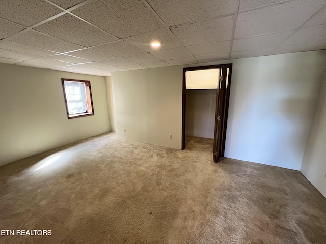 carpeted spare room featuring a drop ceiling