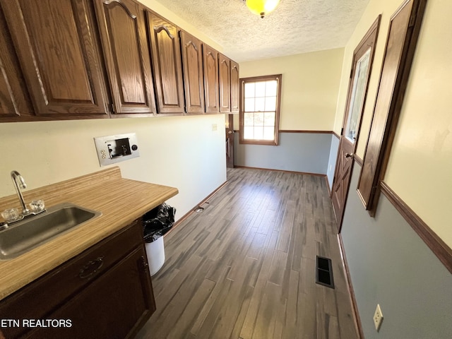 kitchen featuring visible vents, dark wood finished floors, a sink, light countertops, and a textured ceiling