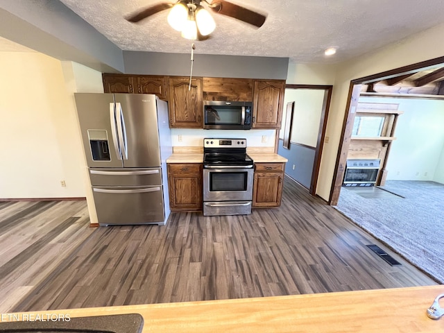 kitchen featuring visible vents, light countertops, stainless steel appliances, a textured ceiling, and dark wood-style flooring