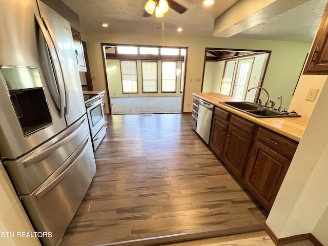 kitchen with a sink, a textured ceiling, wood finished floors, recessed lighting, and appliances with stainless steel finishes