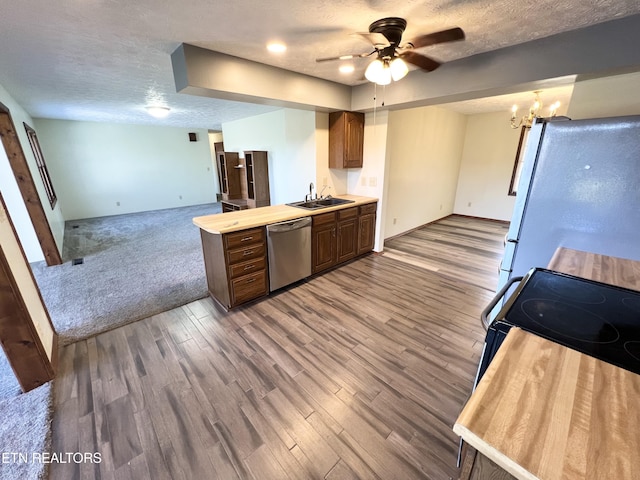 kitchen featuring wood finished floors, a sink, light countertops, appliances with stainless steel finishes, and a textured ceiling