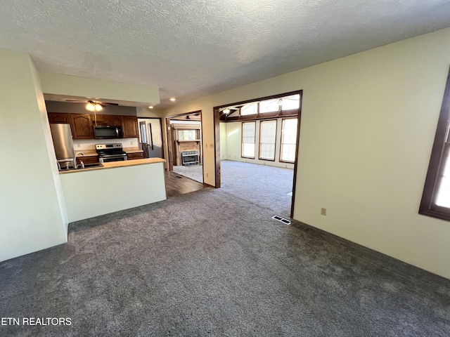 kitchen featuring visible vents, open floor plan, dark carpet, appliances with stainless steel finishes, and a peninsula