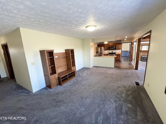 unfurnished living room with visible vents, a textured ceiling, and carpet flooring