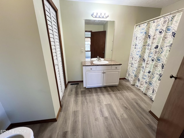 bathroom with vanity, a shower with curtain, wood finished floors, and baseboards