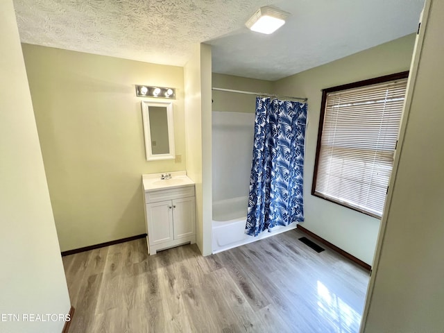 bathroom featuring vanity, wood finished floors, visible vents, shower / tub combo, and a textured ceiling