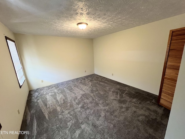 empty room featuring dark colored carpet and a textured ceiling