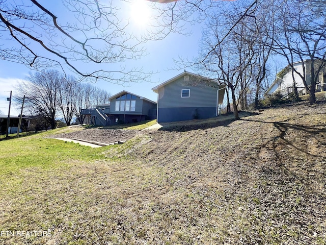 view of property exterior with a yard and stairway