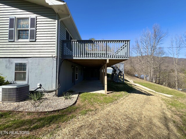 view of side of property featuring cooling unit, a patio, a lawn, and a deck