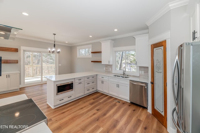 kitchen with a sink, open shelves, appliances with stainless steel finishes, and a peninsula