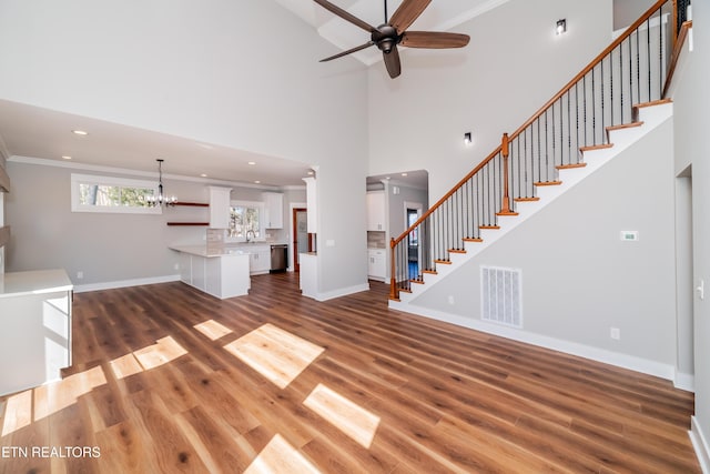 unfurnished living room featuring visible vents, stairs, baseboards, and wood finished floors