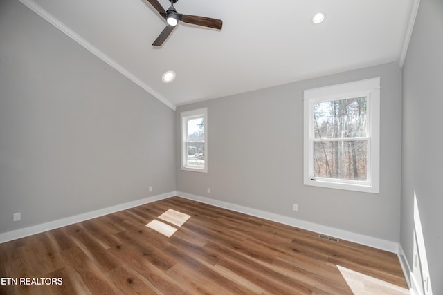 empty room featuring ceiling fan, visible vents, baseboards, and wood finished floors