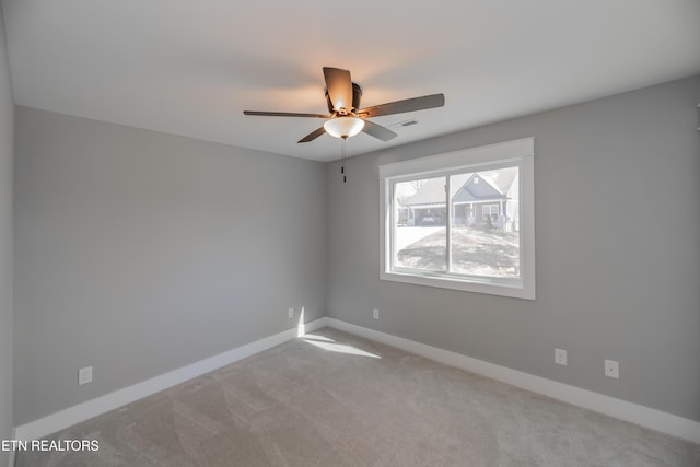 carpeted spare room featuring baseboards and a ceiling fan