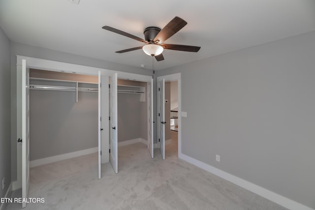 unfurnished bedroom with baseboards, carpet floors, two closets, and ceiling fan