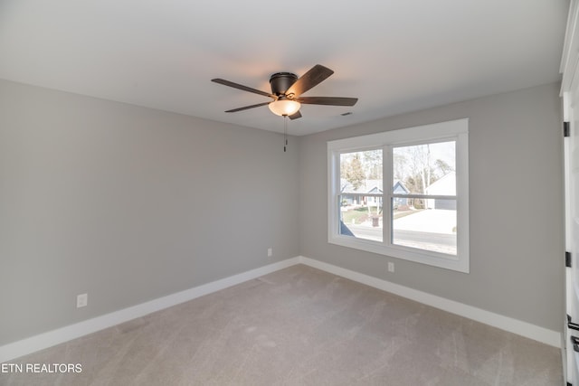 unfurnished room featuring a ceiling fan, light colored carpet, and baseboards