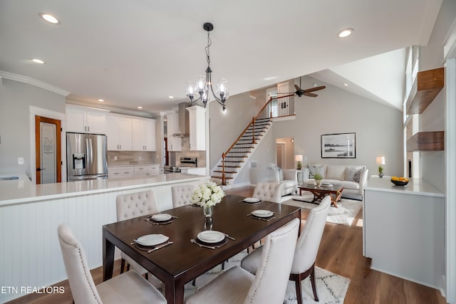 dining area featuring stairs, vaulted ceiling, recessed lighting, ceiling fan with notable chandelier, and dark wood-style flooring