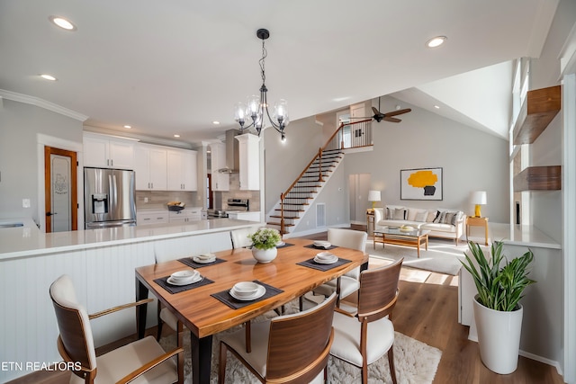 dining room featuring stairway, vaulted ceiling, recessed lighting, ceiling fan with notable chandelier, and wood finished floors