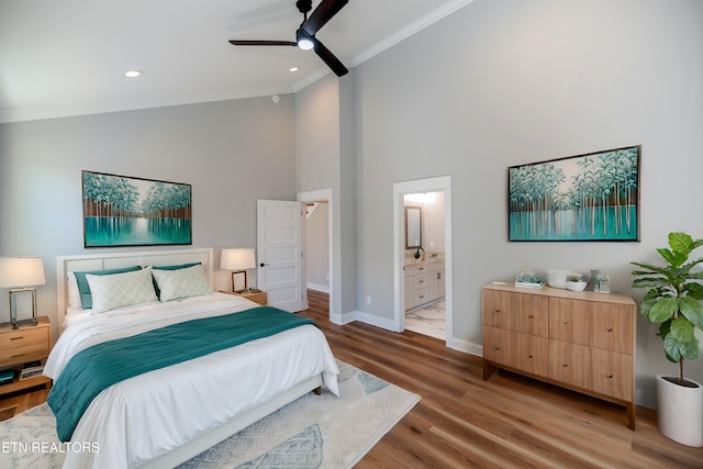 bedroom with baseboards, ornamental molding, ensuite bathroom, wood finished floors, and high vaulted ceiling