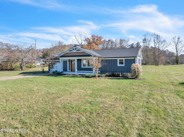 view of front facade featuring an attached garage, driveway, a front yard, and board and batten siding