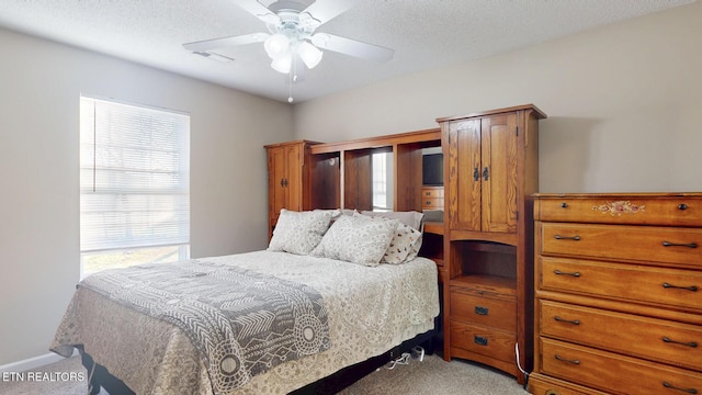 bedroom featuring light carpet, visible vents, a textured ceiling, and ceiling fan