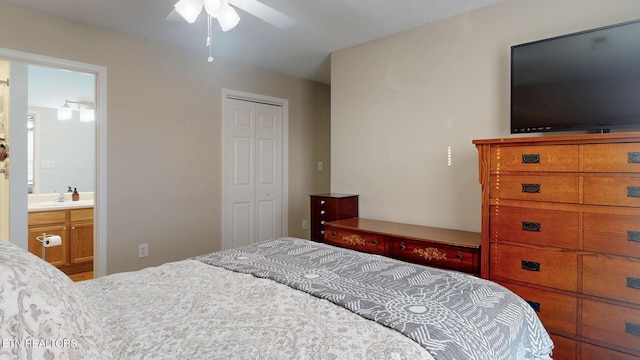 bedroom featuring a ceiling fan, a closet, ensuite bathroom, and a sink