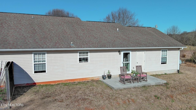 rear view of house featuring a yard, a patio, and a shingled roof