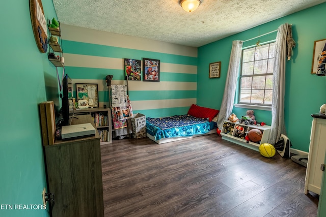 bedroom featuring baseboards, a textured ceiling, and wood finished floors