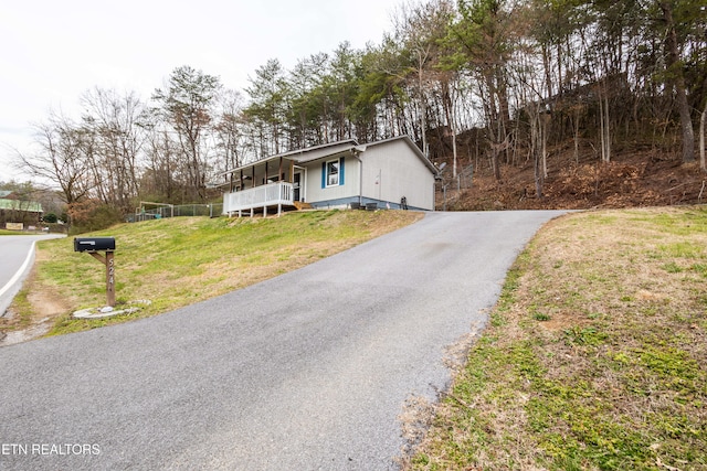 view of front of home with driveway, covered porch, and a front yard