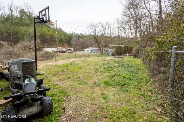 view of yard featuring cooling unit, fence, and a playground