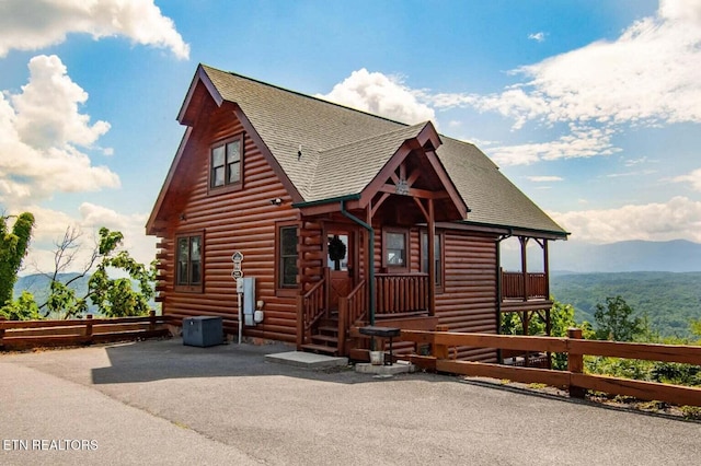 log-style house with entry steps, fence, a mountain view, a shingled roof, and log siding