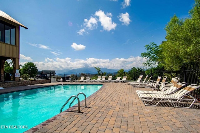 community pool featuring a mountain view, a patio, and fence