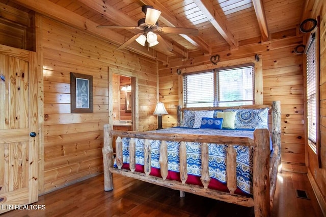 bedroom featuring beamed ceiling, wooden walls, and visible vents