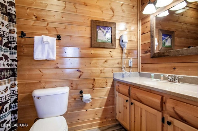 full bathroom featuring wooden walls, vanity, and toilet